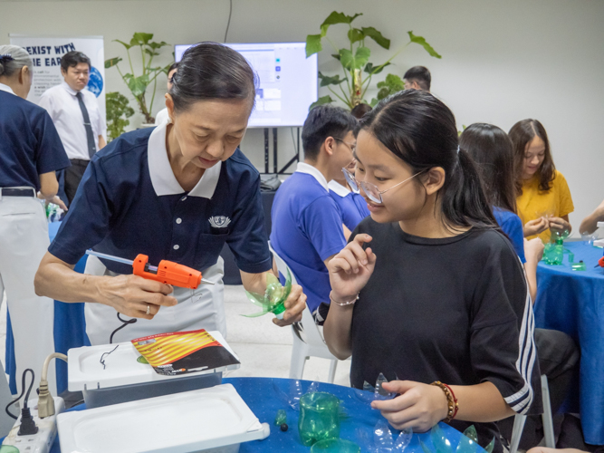 A Tzu Chi volunteer assists an ISM student in the upcycling activity. 