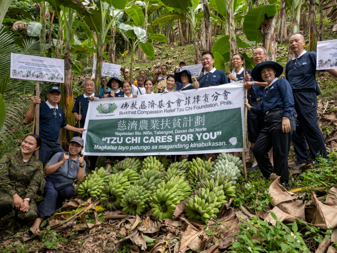 Tzu Chi volunteers gather for a group photo alongside farmers proudly displaying their banana harvests. 【Photo by Matt Serrano】